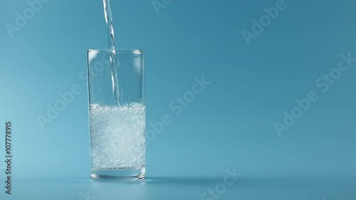 Mineral water pouring in glass in blue background
