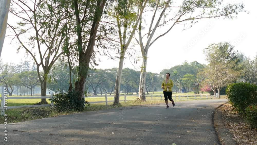 woman drinking during jogging in park woman drinking during jogging in park