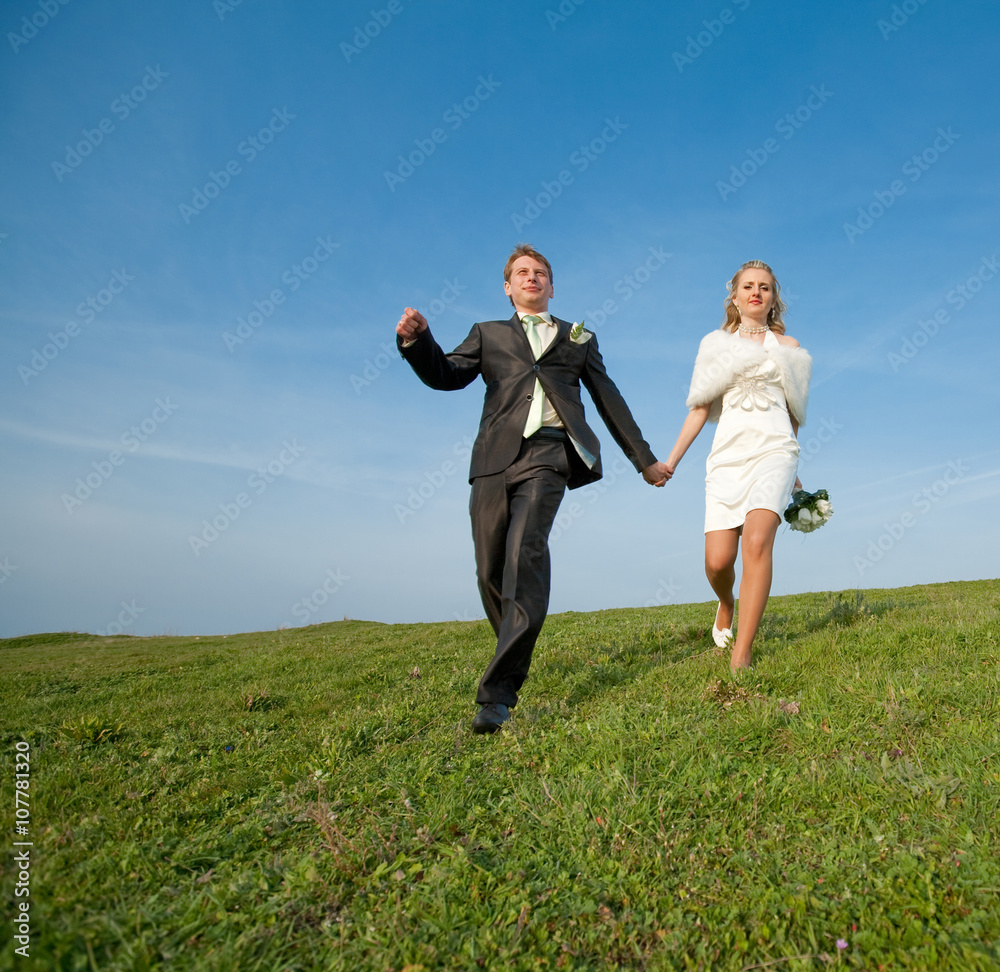 Newly wedded running along the field