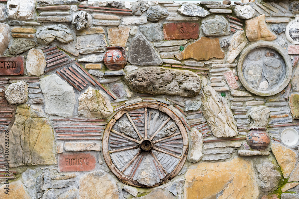Background. A stone wall with a wooden wheel and a jug