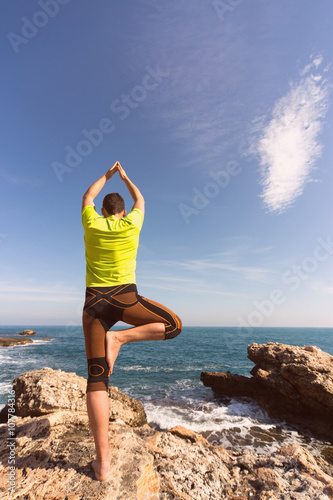 young man doing yoga exercises on the beach.