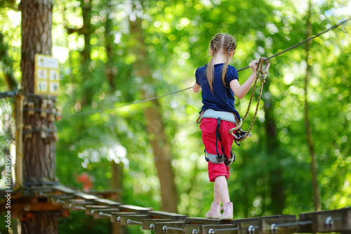 Adorable little girl enjoying her time in climbing adventure park