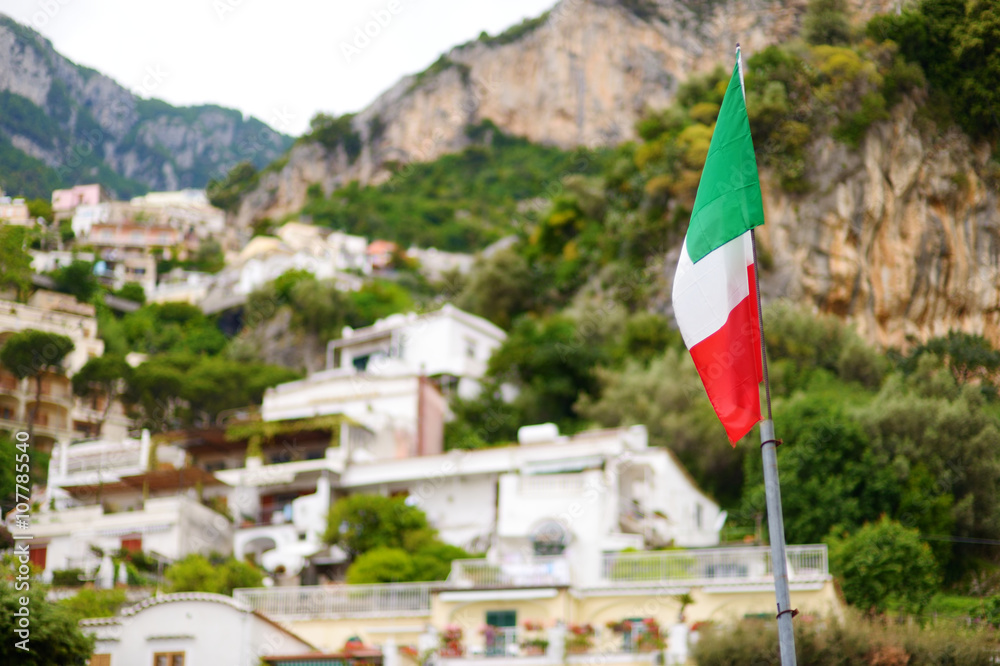 Italian flag over beautiful town of Positano at famous Amalfi coast