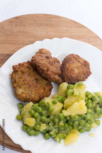 Homemade burgers served with potatoes and green peas