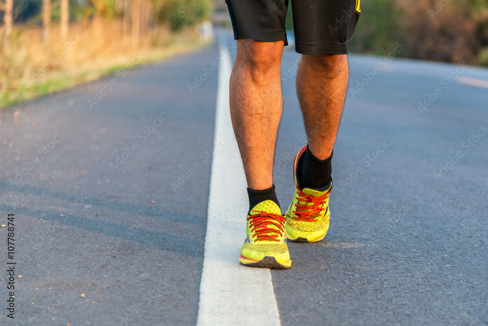 Runner man feet running on road closeup on shoe. Male fitness mo Runner man feet running on road closeup on shoe. Male fitness mo