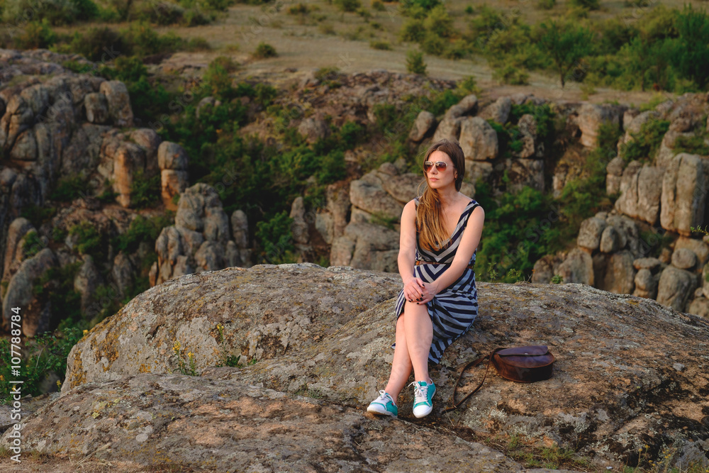 happy girl sits on a background of the canyon