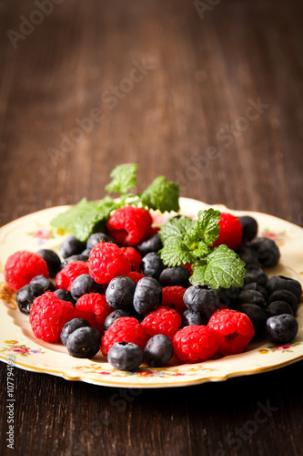 blueberries and raspberries on a plate ventazhnoy dark wood back