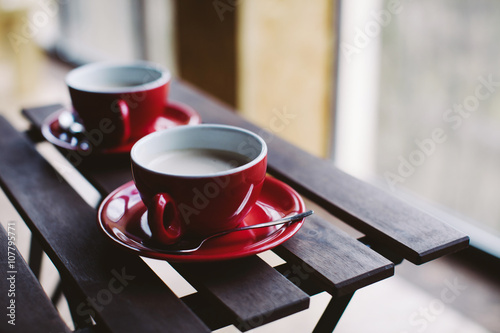Two red cups on wooden plank table