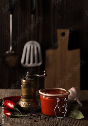 Dark still life with chili pepper hot sauce and ingredients