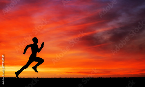 Silhouette of running man against the colorful sky. 