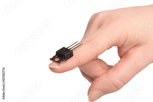 Close-up view of young girl hand holding transistor based microchip and gesturing with it, taken on white background. Nanotechnology concept