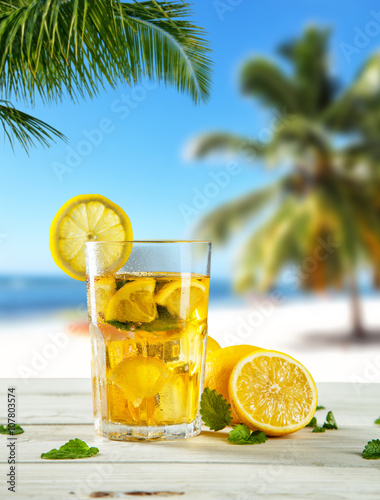 Glass of summer ice tea drink on beach
