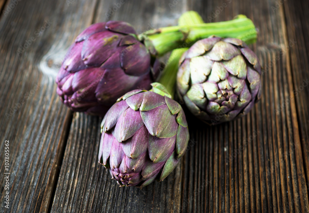 Obraz premium Organic Artichokes on rustic wooden board