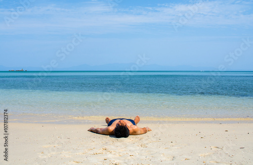 Man with no shirt lay down on the beach