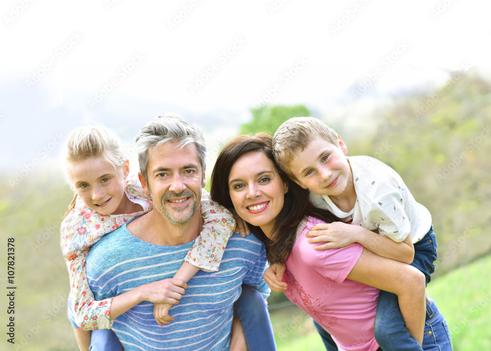 Parents giving piggyback ride to kids outside Parents giving piggyback ride to kids outside