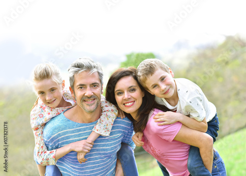Parents giving piggyback ride to kids outside