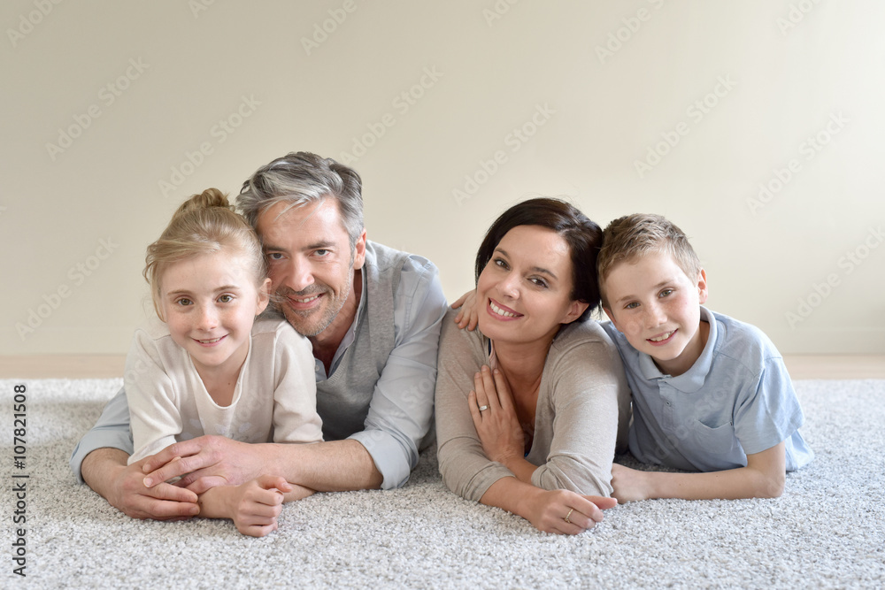 Portrait of cheerful family laying on carpet Portrait of cheerful family laying on carpet