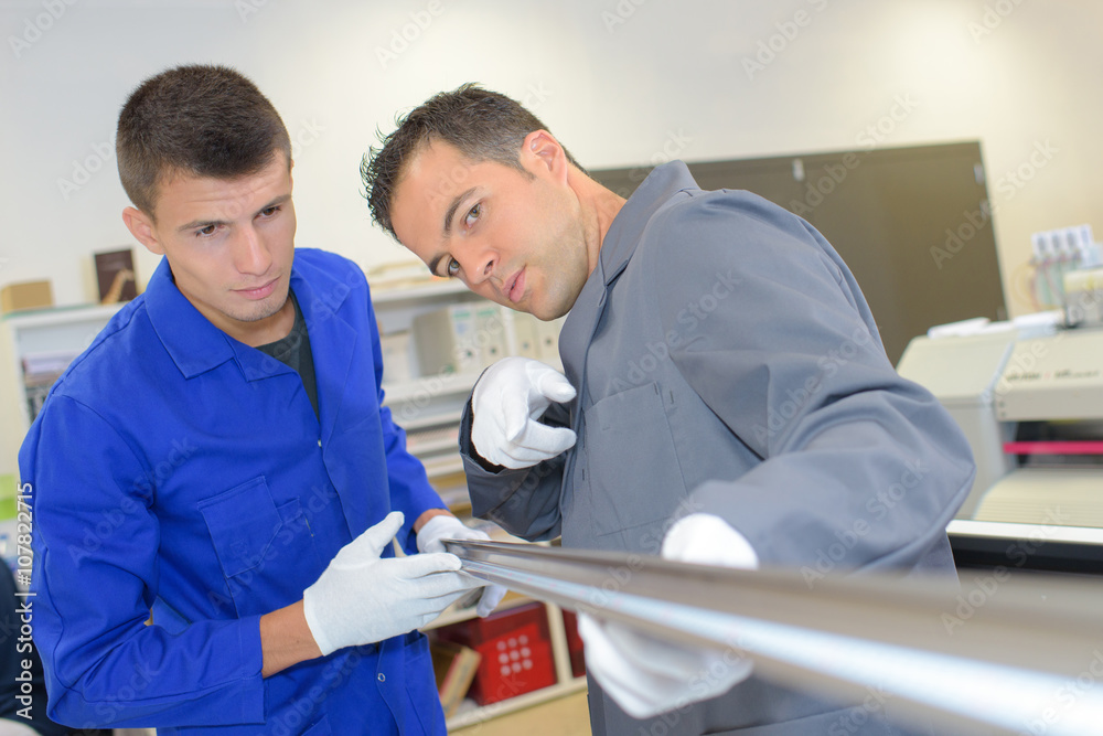 Obraz premium Two men looking down the length of a metal pole