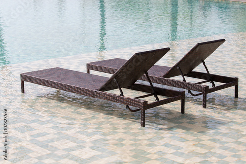 Swimming pool and two deck chairs, close up