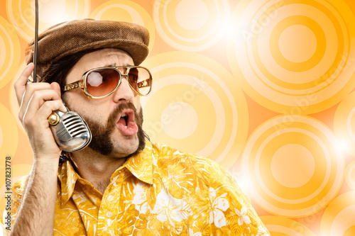 1970s vintage show man sing with hawaiian shirt and microphone on yellow background