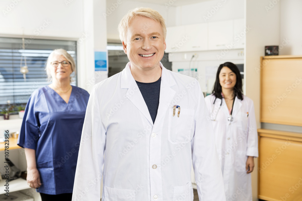 Medical Professional Smiling While Standing With Team In Clinic