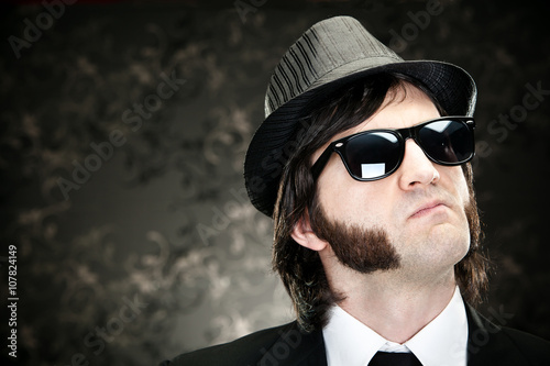 elegant boss man with sideburns and sunglasses on black backround photo