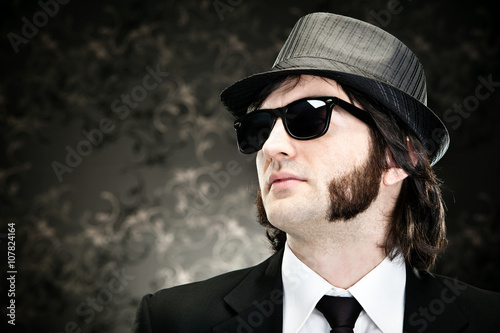 elegant boss man with sideburns and sunglasses on black backround photo