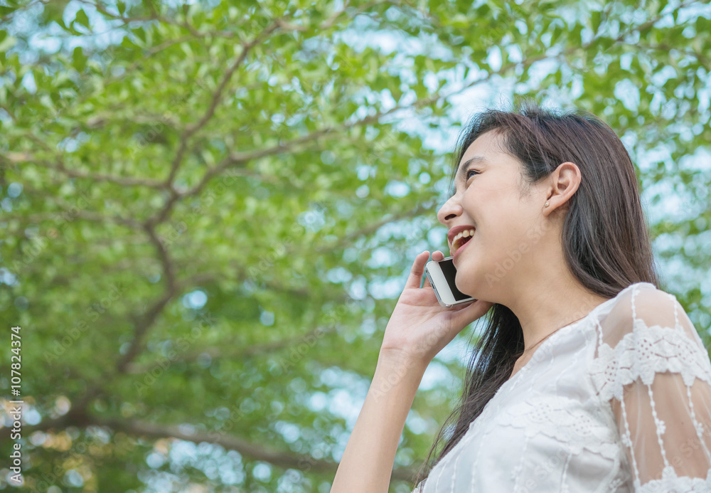 Asian woman chat with mobile phone in happy emotion in park Asian woman chat with mobile phone in happy emotion in park