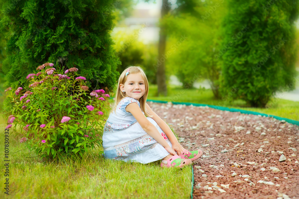 Little blond girl in white dress sitting on green grass in bloss Stock ...
