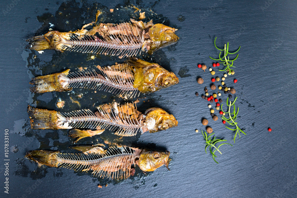 Foto Stock top view of fish skeleton bones and flavor peppers on slate