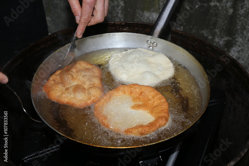 Cook hands while cooking the fried fritters dipped in boiling oi photo