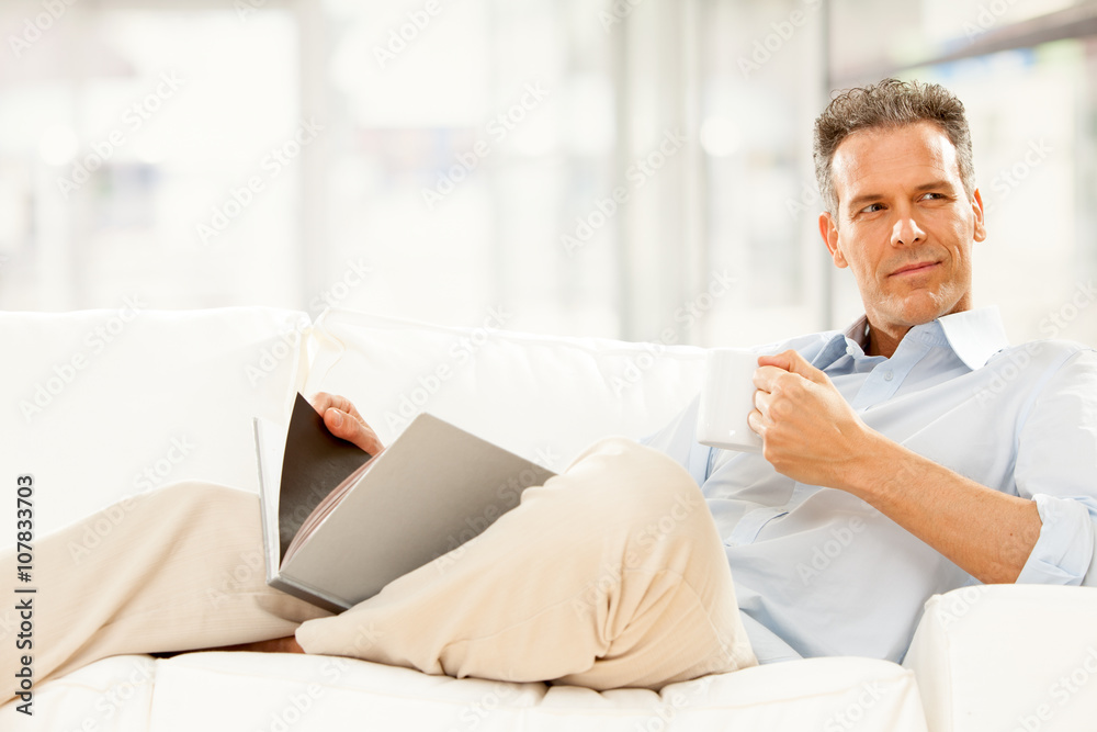 handsome businessman read and drink cup of tea on the couch at home handsome businessman read and drink cup of tea on the couch at home
