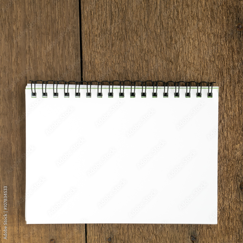 The close up of blank white notebook on wooden plank background. The close up of blank white notebook on wooden plank background.