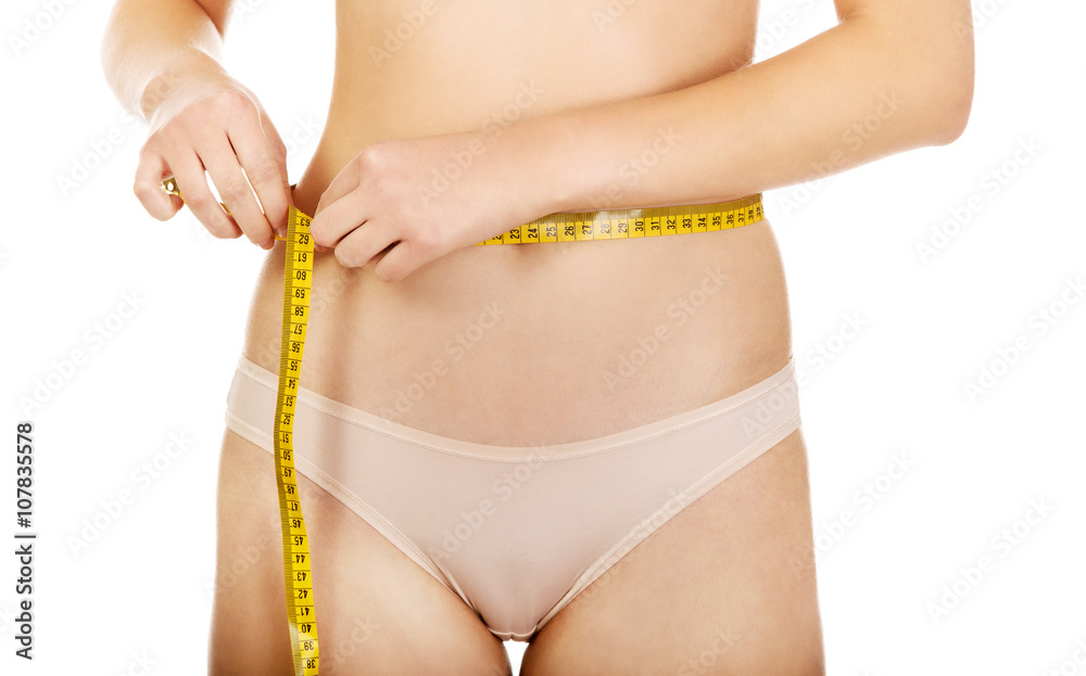 Fit woman measuring her waist with a tape measure