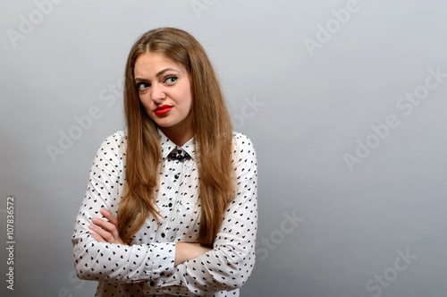 Photography Girl with condemning glance, crossed hands on grey background