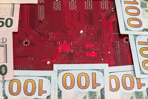 Closeup of one hundred dollar with red computer motherboard