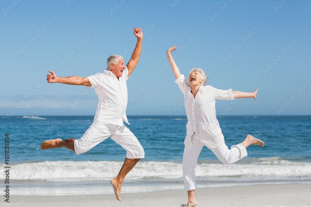 Senior couple jumping at the beach