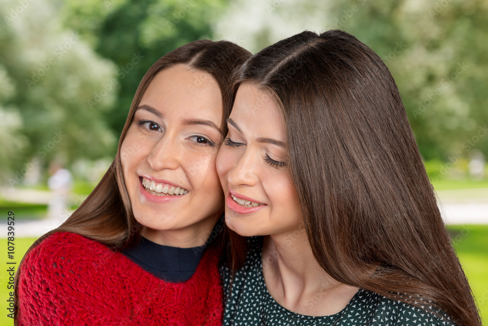 Two beautiful sisters hugging each other and smiling