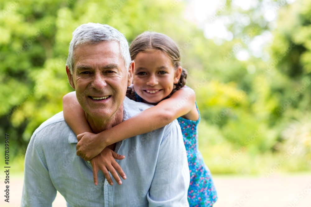 Grandfather carrying grandaughter in yard 