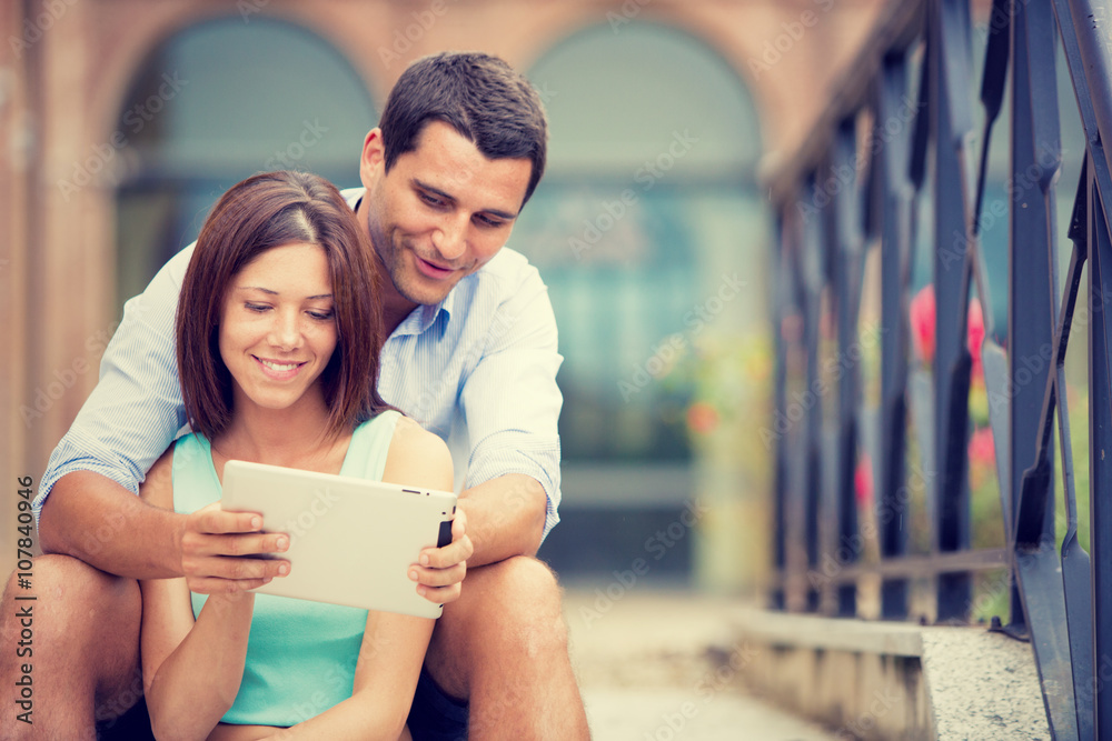 young brunette couple having fun together with tablet at park young brunette couple having fun together with tablet at park