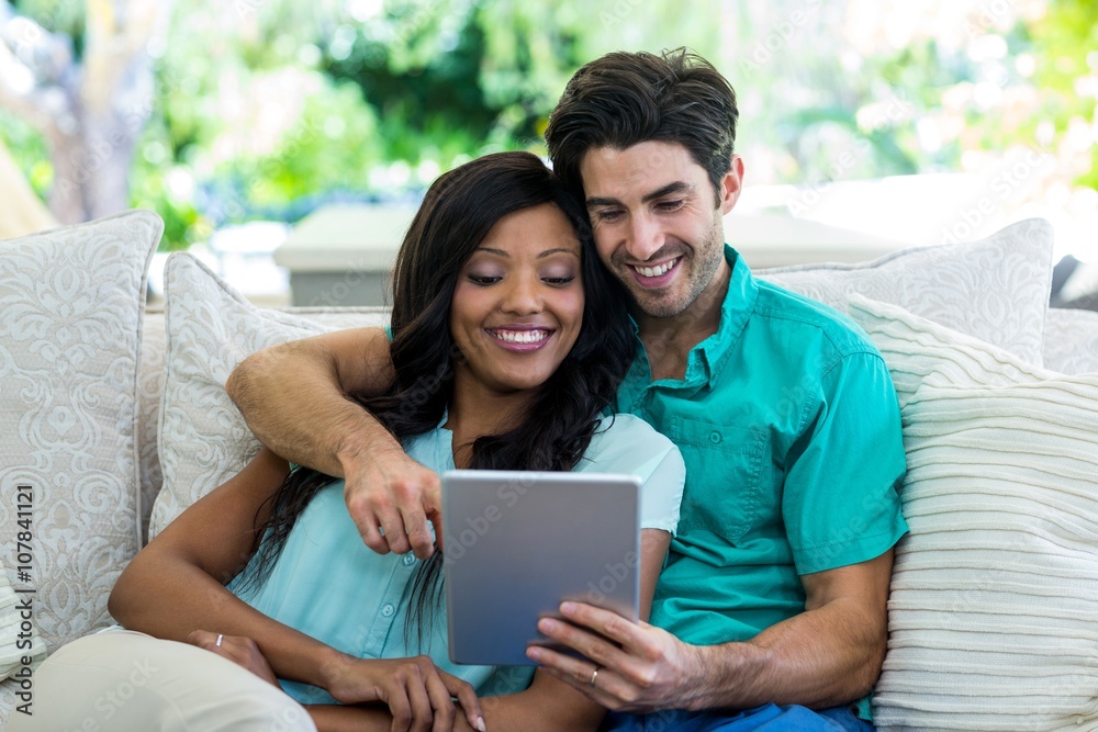 Young couple sitting on sofa and using digital tablet Young couple sitting on sofa and using digital tablet