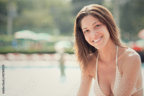 Beautiful girl in bikini at swimming pool outdoor