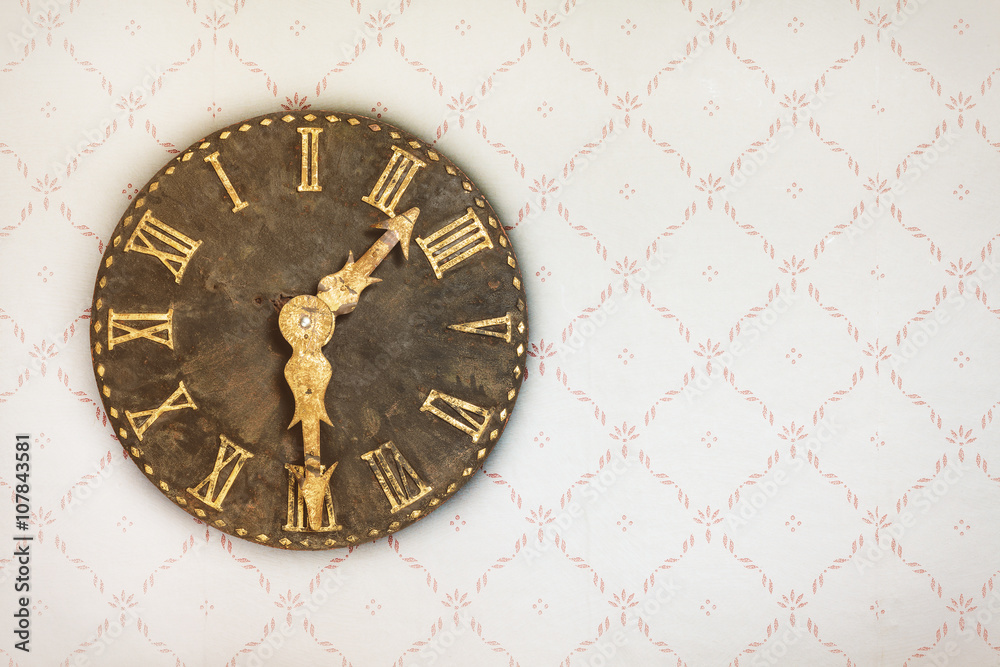 Vintage clock on a wall with retro wallpaper