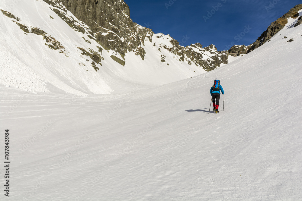 Mountaineer goes through the valley in winter conditions.