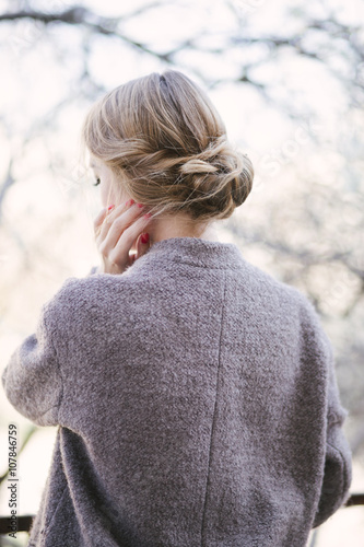 Young beautiful woman near trees in blossom in the spring time. Hair style bun