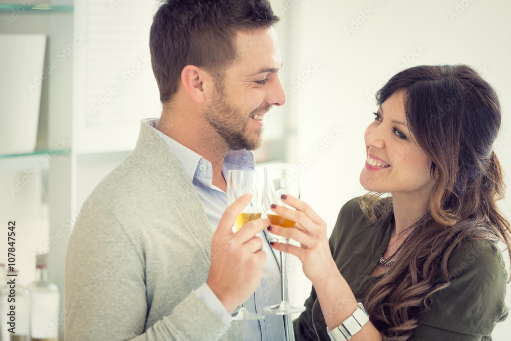 young casual couple cheers with champagne in the kitchen young casual couple cheers with champagne in the kitchen