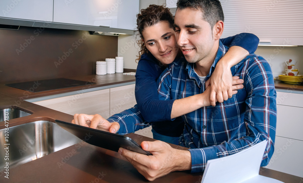 Cheerful couple using digital tablet at kitchen home Cheerful couple using digital tablet at kitchen home