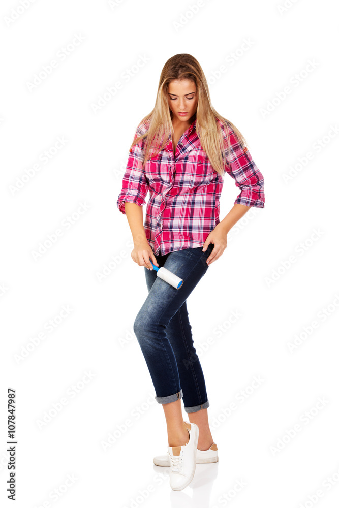Young woman cleaning her shirt with lint roller Young woman cleaning her shirt with lint roller