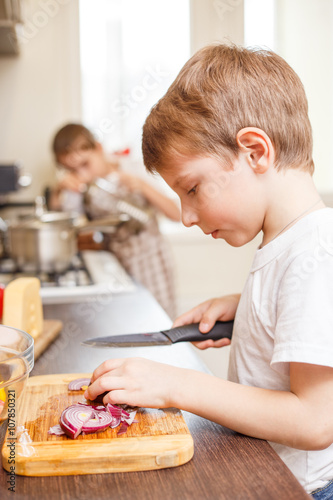 Small boy cooking together with his sister