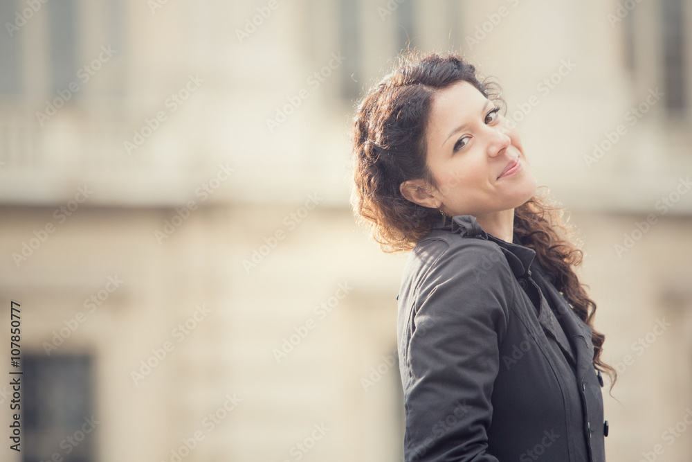 smiling curly woman in cityscape